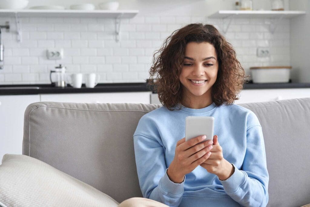 Young, adult woman smiling at her phone