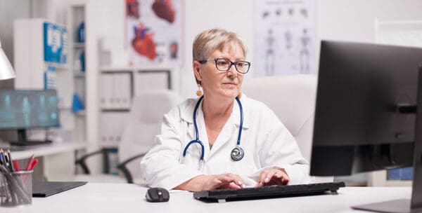 Mature,Female,Doctor,Using,Computer,In,Hospital,Cabinet.